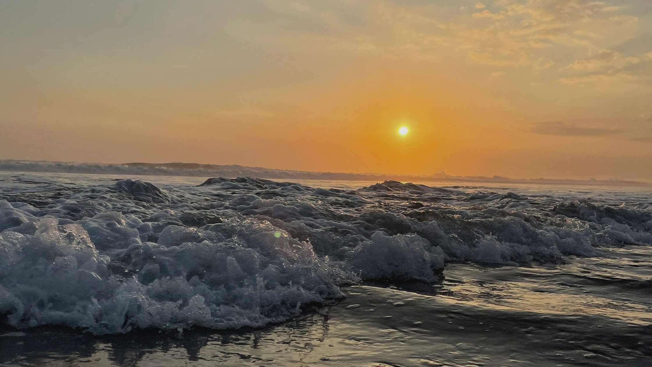 Powerful ocean waves glowing under a golden sunset sky