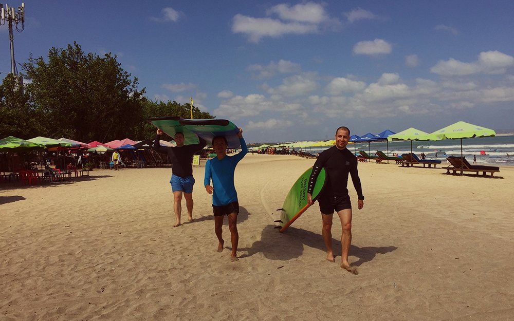 Surfers carrying boards along the beach in Bali, Indonesia